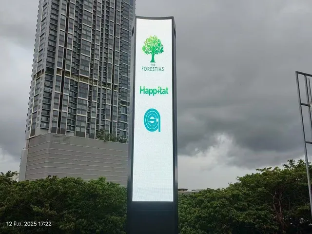 Layar LED lengkung dua sisi berbentuk menara jam di kawasan The Forestias Bangkok menyala pada senja hari