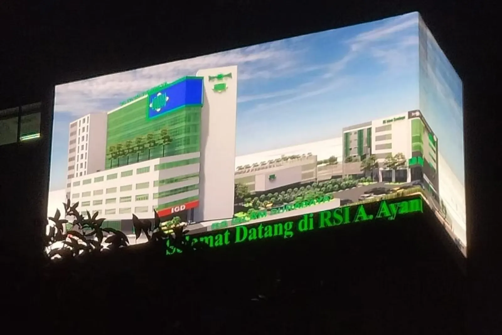 Videotron fasad di sudut gedung Rumah Sakit Islam A. Yani Surabaya menayangkan visual gedung rumah sakit pada malam hari