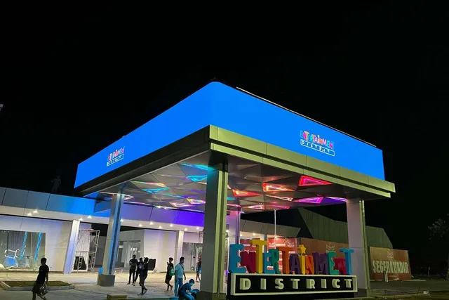 Gerbang Entertainment District PIK 2 Banten pada malam hari dengan signage LED biru menyala di atas kanopi
