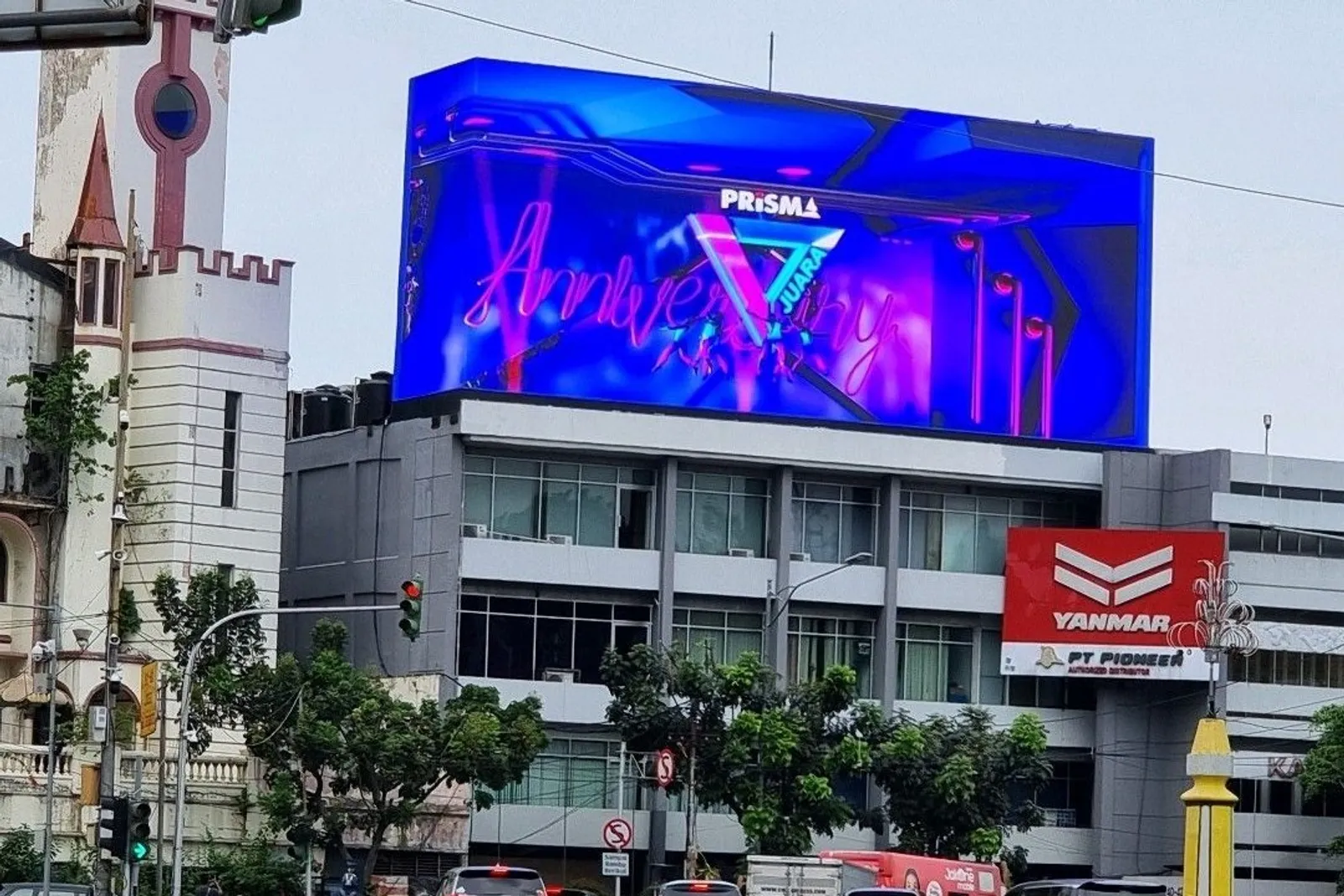 Videotron P6.67 menyala di atas gedung kawasan Harmoni Jakarta Pusat, dengan lalu lintas padat dan bangunan tua di sekitarnya