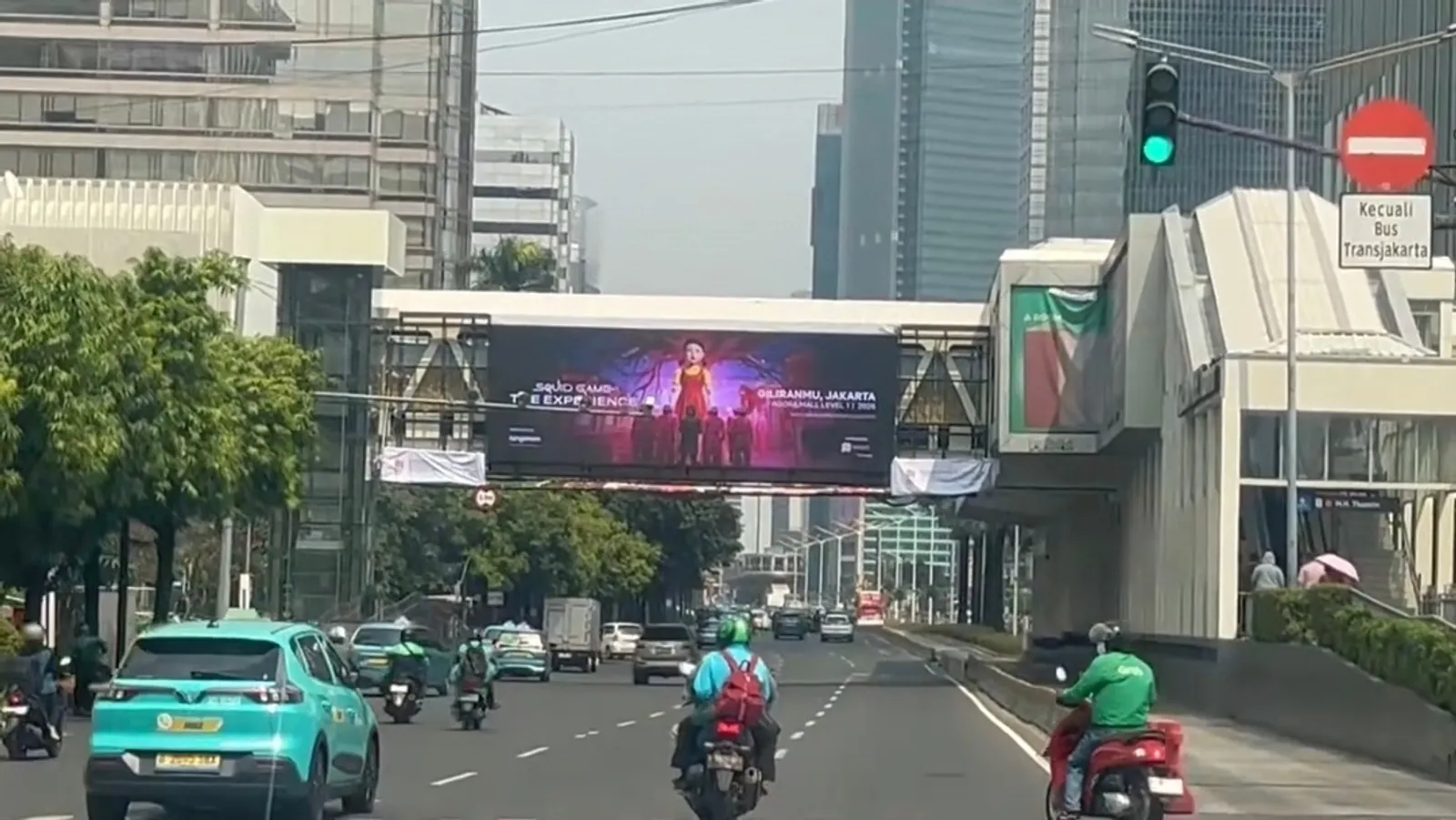 LED bando halte Transjakarta M.H. Thamrin menayangkan poster konser, dengan gedung perkantoran Jakarta di latar belakang