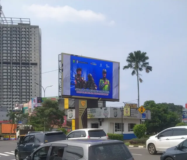 Billboard videotron Jalan Raya Serpong dilihat dari arah berlawanan, dengan lalu lintas padat dan gedung tinggi di latar