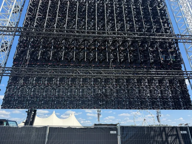 Kru memasang kabinet LED Master Pro Touring pada rigging panggung festival